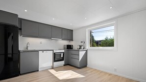A modern kitchen with grey cabinets, a black refrigerator, a microwave, and a coffee maker. - Entire Single-family Home - Centrally Located in Voss (Voss)