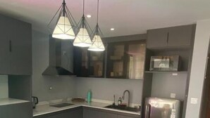 Una cocina moderna con una isla central, taburetes de bar, iluminación colgante y electrodomésticos integrados.