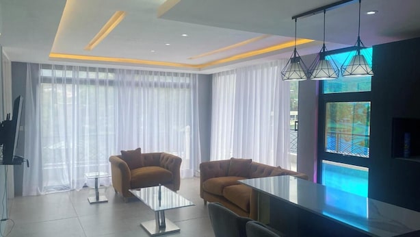 Una sala de estar moderna con una mesa de centro de vidrio, dos sofás y un comedor con barra.