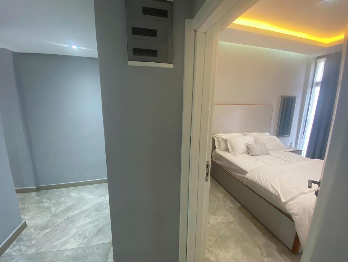 Une chambre d’hôtel moderne, équipée d’un lit, d’une table de chevet et d’une fenêtre avec des rideaux.
