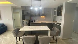 Una cocina moderna con una isla central, cuatro sillas grises y una mesa de comedor.