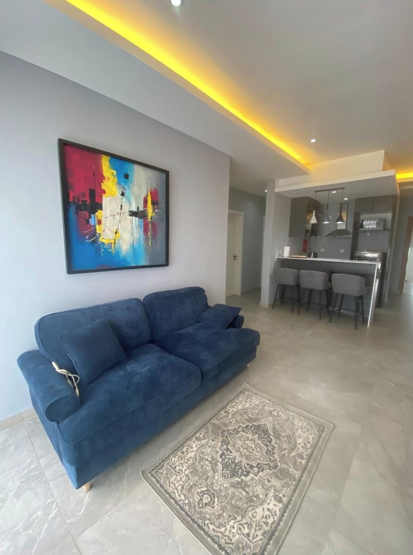 Una sala de estar moderna con un sofá azul, un tapete estampado y un cuadro abstracto colorido en la pared.