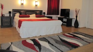 Een netjes ingerichte slaapkamer met een groot bed, nachtkastjes, een flatscreen televisie en een decoratieve vaas.