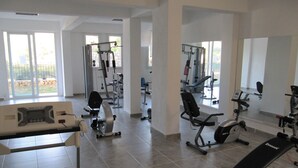 Een ruime fitnessruimte met diverse trainingsapparaten, grote ramen en een schoon, modern design.