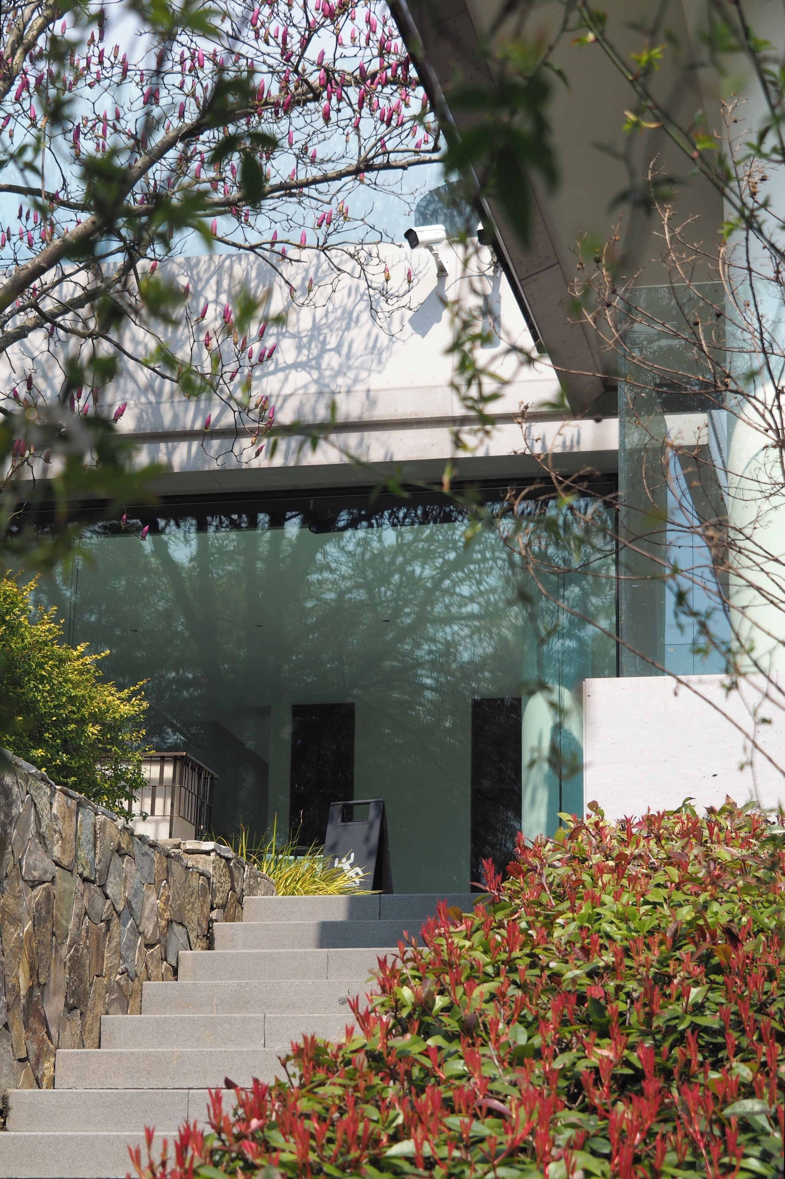 A modern building with a stone wall and a staircase leading to a door.