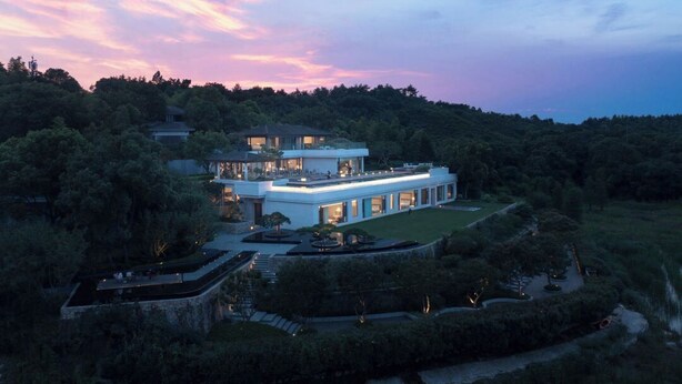 A modern, multi-story house with a spacious outdoor area, surrounded by dense greenery. - FU VALLEY (Changzhou)