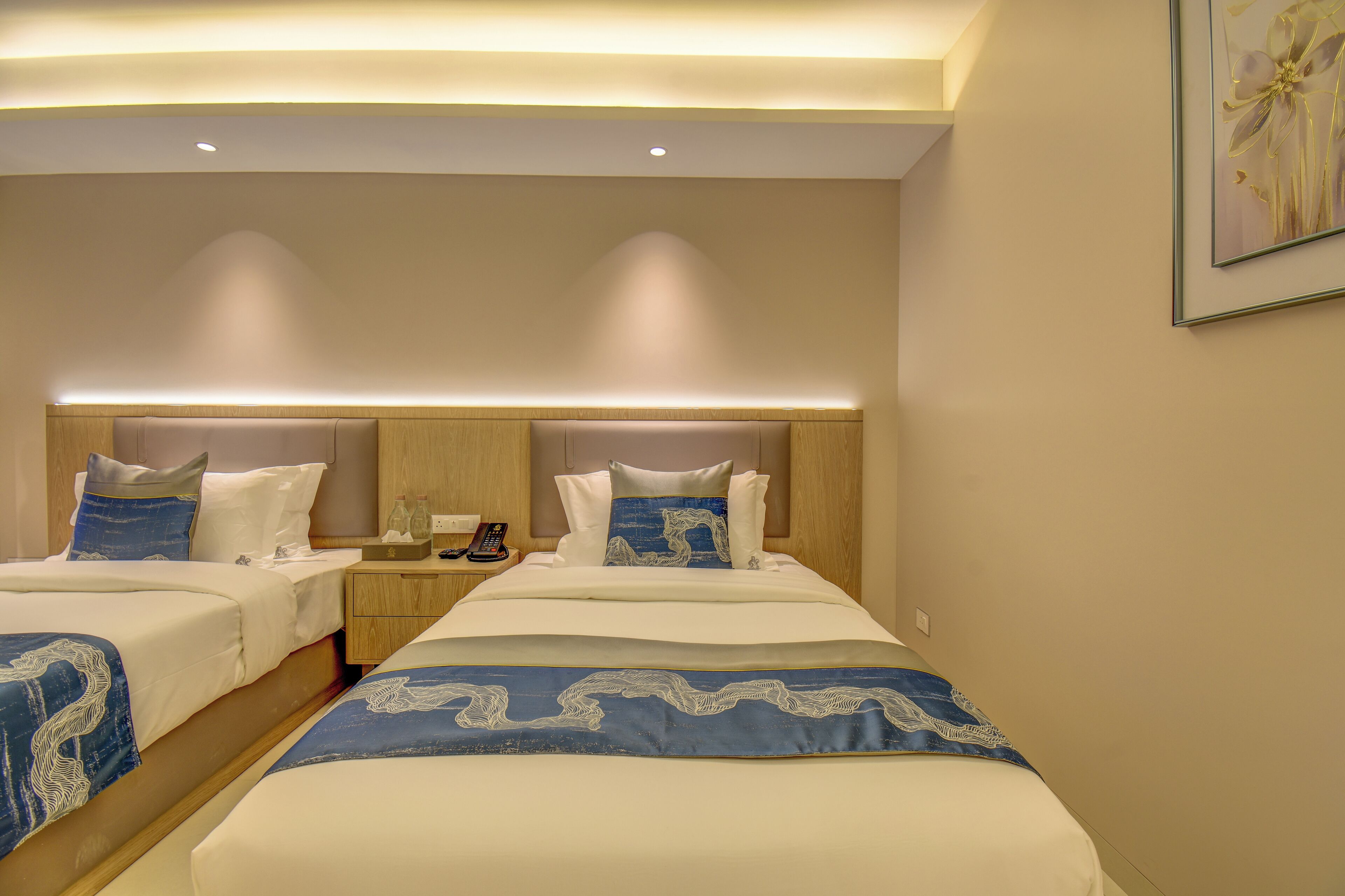 A hotel room with two beds, each with a headboard, bedside tables, and a nightstand.