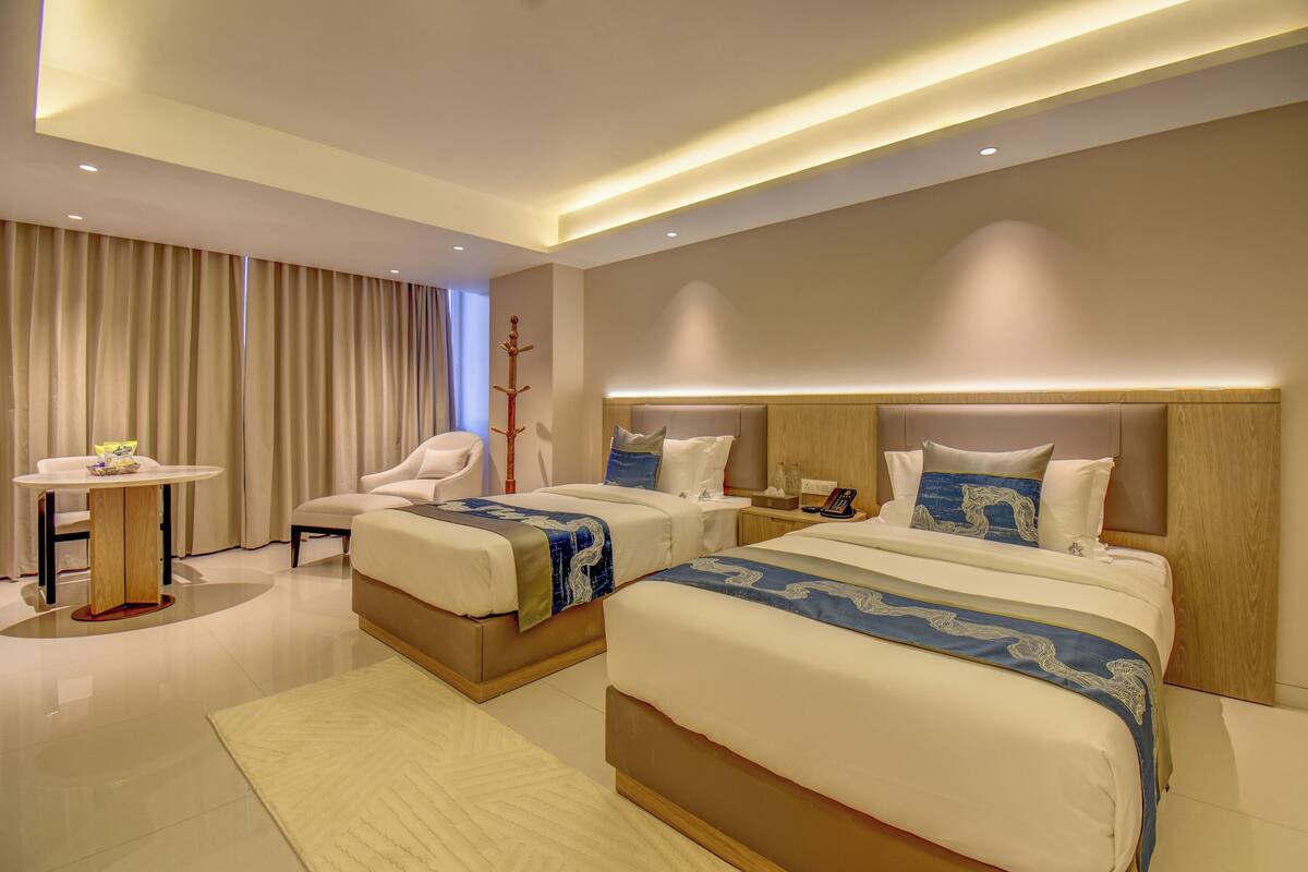 Een moderne hotelkamer met twee bedden, een tafeltje en een stoel.
