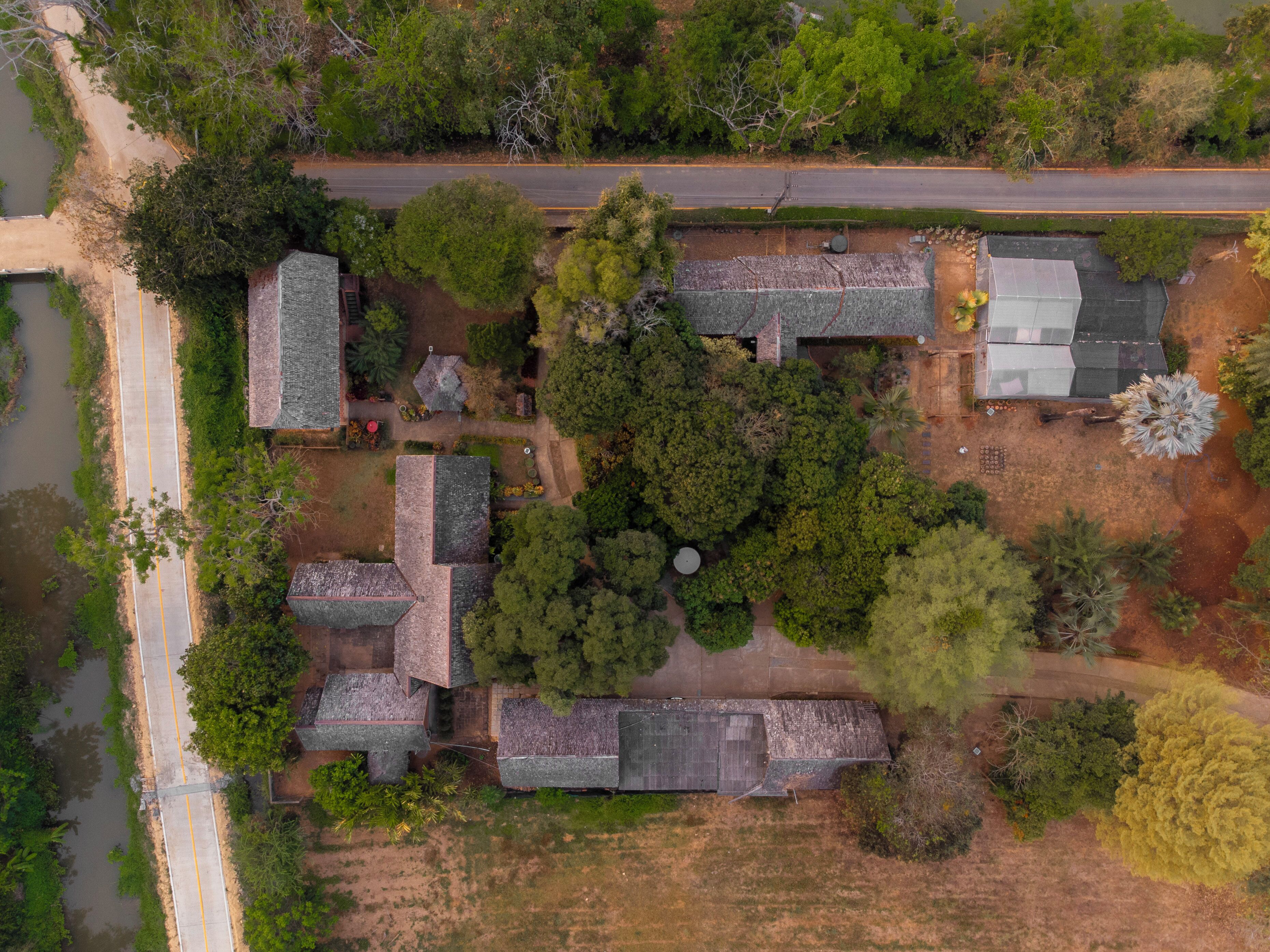 An aerial view of a residential area with multiple houses, a road, and a river.