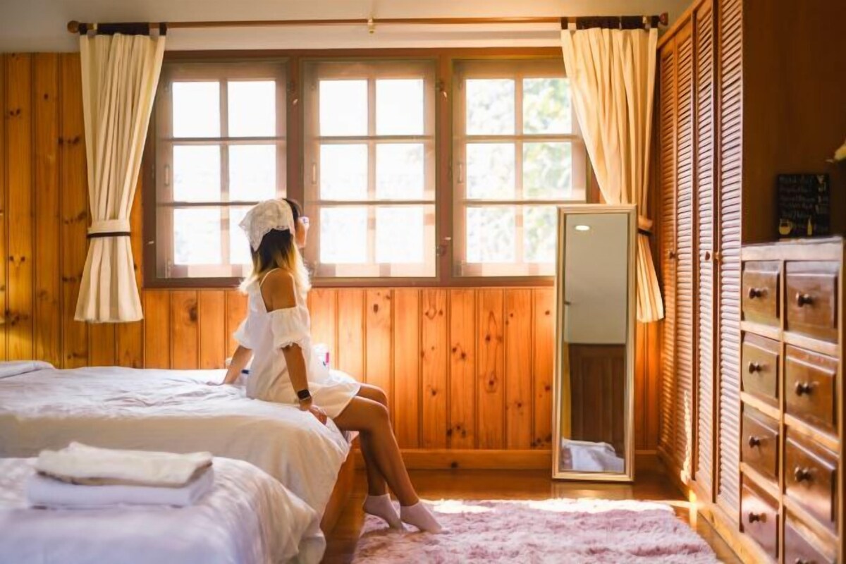 A room with wooden paneling, a bed, a dresser, and a mirror.