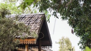 A wooden structure with intricate carvings, a staircase, and potted plants. - Ban MaeBo Local Stay (Mae Rim)
