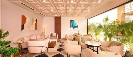 A modern hotel lobby with a geometric patterned floor, contemporary furniture, and a large window offering a view of greenery.
