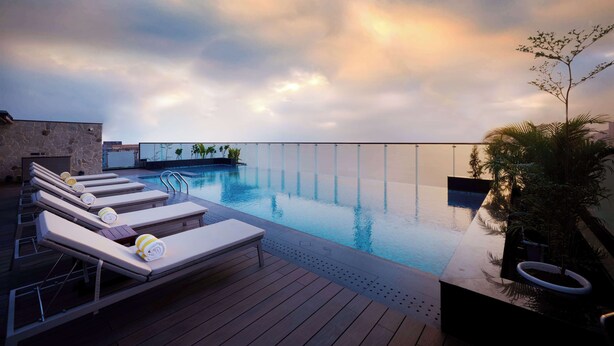 A rooftop infinity pool with lounge chairs and a wooden deck. - Iris Sarovar Portico Sector 85 Gurugram (Gurugram)