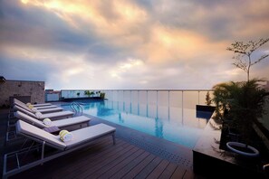A rooftop infinity pool with lounge chairs and a wooden deck. - Iris Sarovar Portico Sector 85 Gurugram (Gurugram)