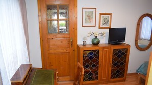 Une porte en bois avec des panneaux de verre, un téléviseur posé sur un meuble et des tableaux encadrés accrochés au mur.