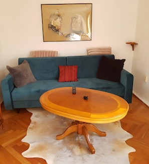 Ein Wohnzimmer mit einem blauen Sofa, einem runden Holztisch und einem Cowhide-Teppich.
