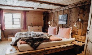 Ein rustikaler Holzraum mit einem Bett, einem Schminktisch und einem Fenster mit Vorhängen.