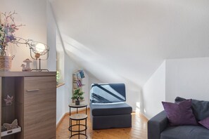 Un salon moderne avec un canapé gris, une petite table ronde et une bibliothèque.