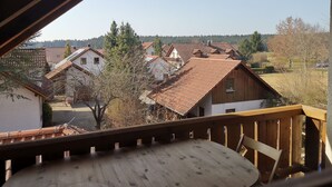 Un balcon en bois donnant sur un quartier résidentiel, avec des maisons et des arbres.