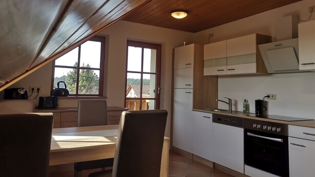 Une cuisine avec un plafond en bois, des placards blancs, un lave-vaisselle et une cuisinière.