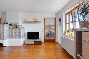 Un salon moderne doté d’un téléviseur à écran plat, de parquet, d’une cheminée et d’une grande fenêtre offrant une vue dégagée.