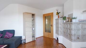 A room with a grey sofa, a wooden cabinet with glass doors, and a wooden floor.