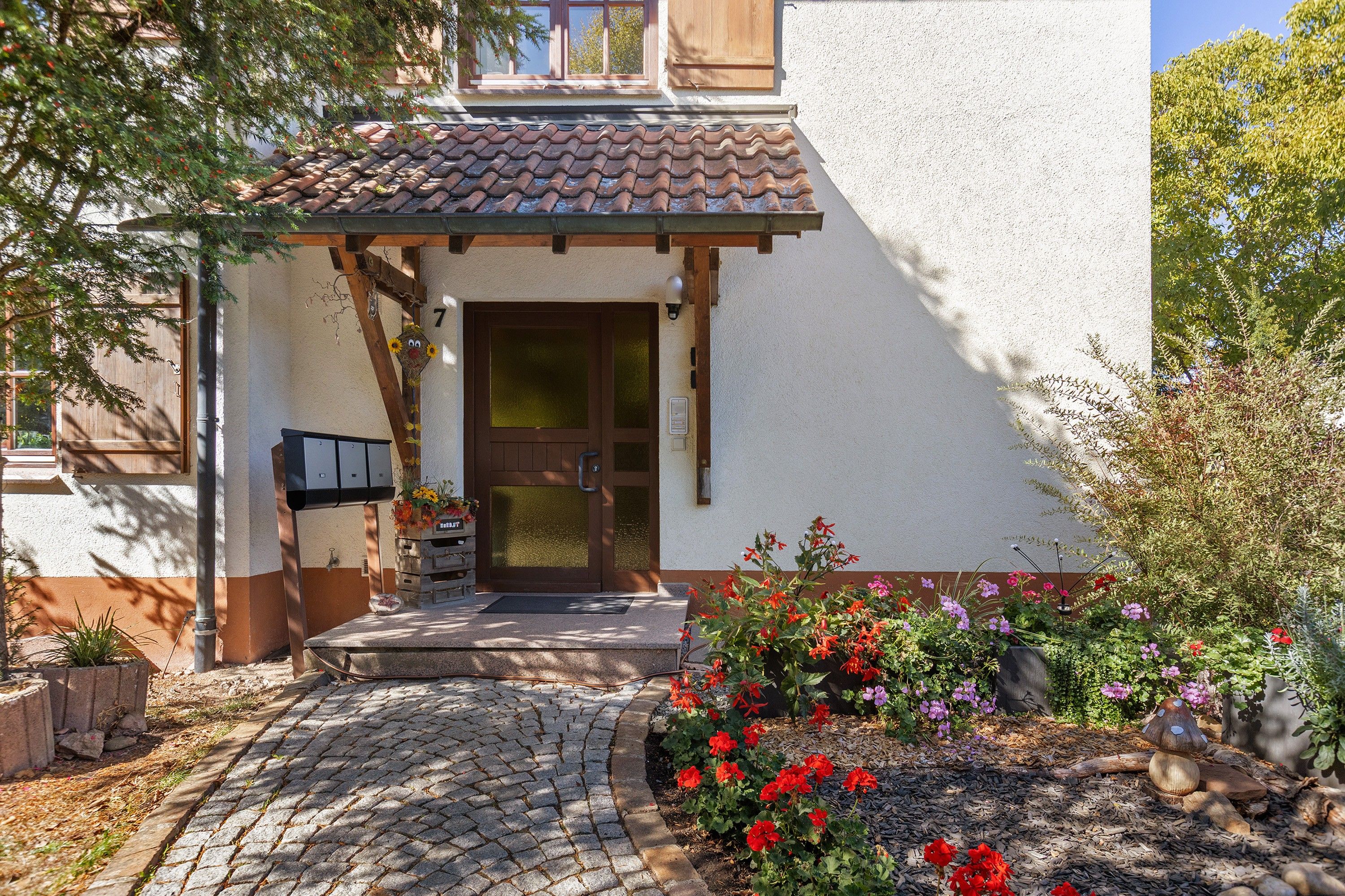 Ein Haus mit Ziegeldach, einer Holztür und einer kleinen Veranda mit einer Bank.