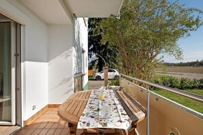 Ein Balkon mit Holztisch, einem Glas und einer blumigen Tischdecke.