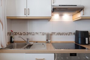 Une cuisine moderne équipée d’un évier en acier inoxydable, d’une plaque de cuisson à induction, d’une machine à café et d’un lave-vaisselle.