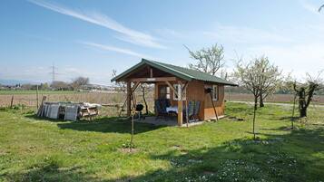 Eine Holzhütte mit einem grünen Dach, einem Tisch, Stühlen und einem kleinen Garten.