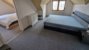 A bedroom with a sloped ceiling, a bed, a dresser, a chair, and a window. - Auenweg Apartment with Shared Pool, Garden, and Wi-Fi (Radebeul)