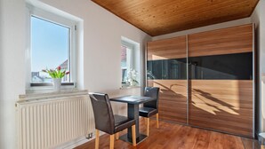 Una habitación moderna con techo de madera, un radiador blanco, una mesa con sillas y una puerta corredera de vidrio.