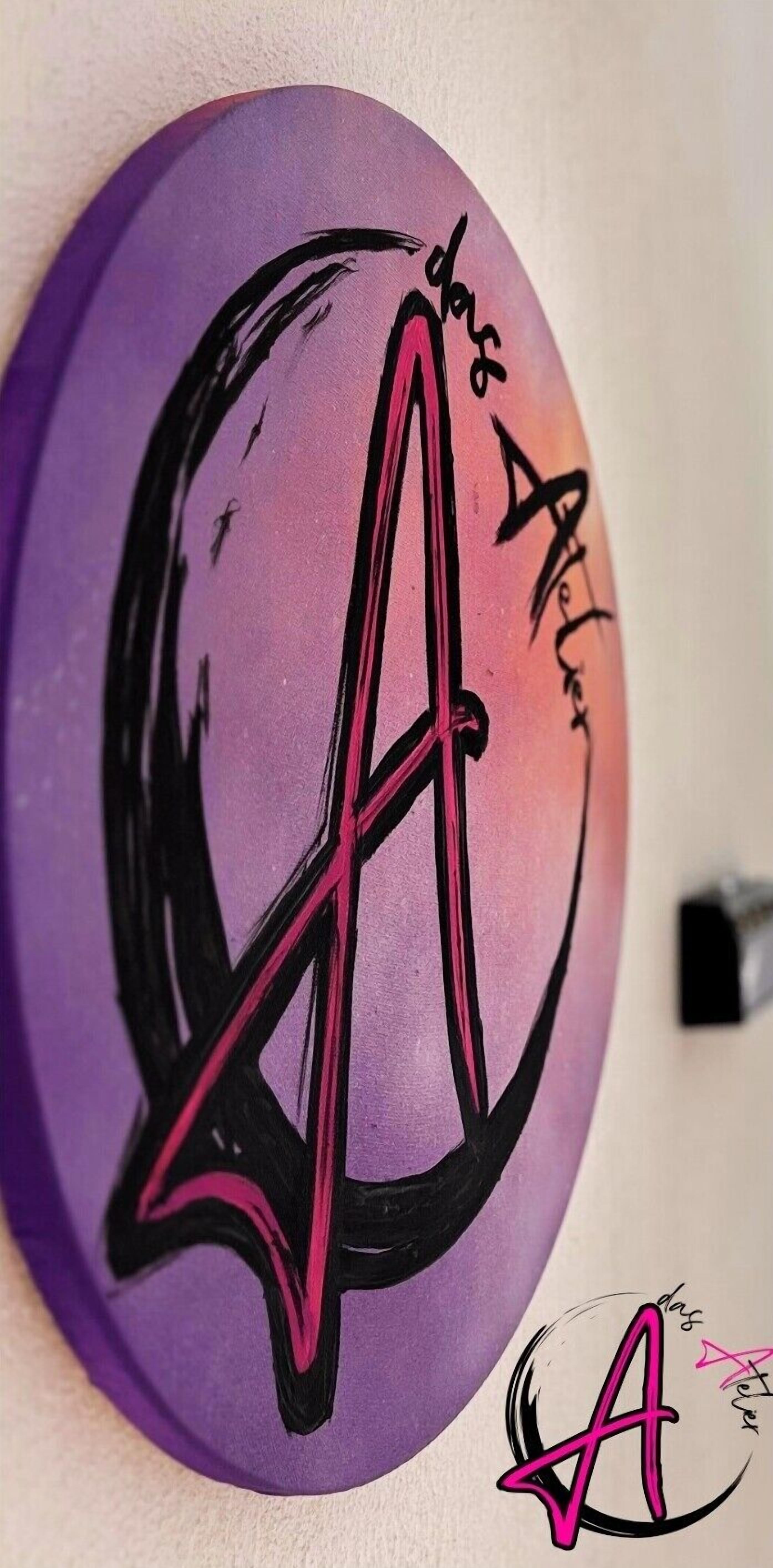 A wall with a circular design featuring a stylized letter 'A' and the text 'das Acker' in a decorative script.