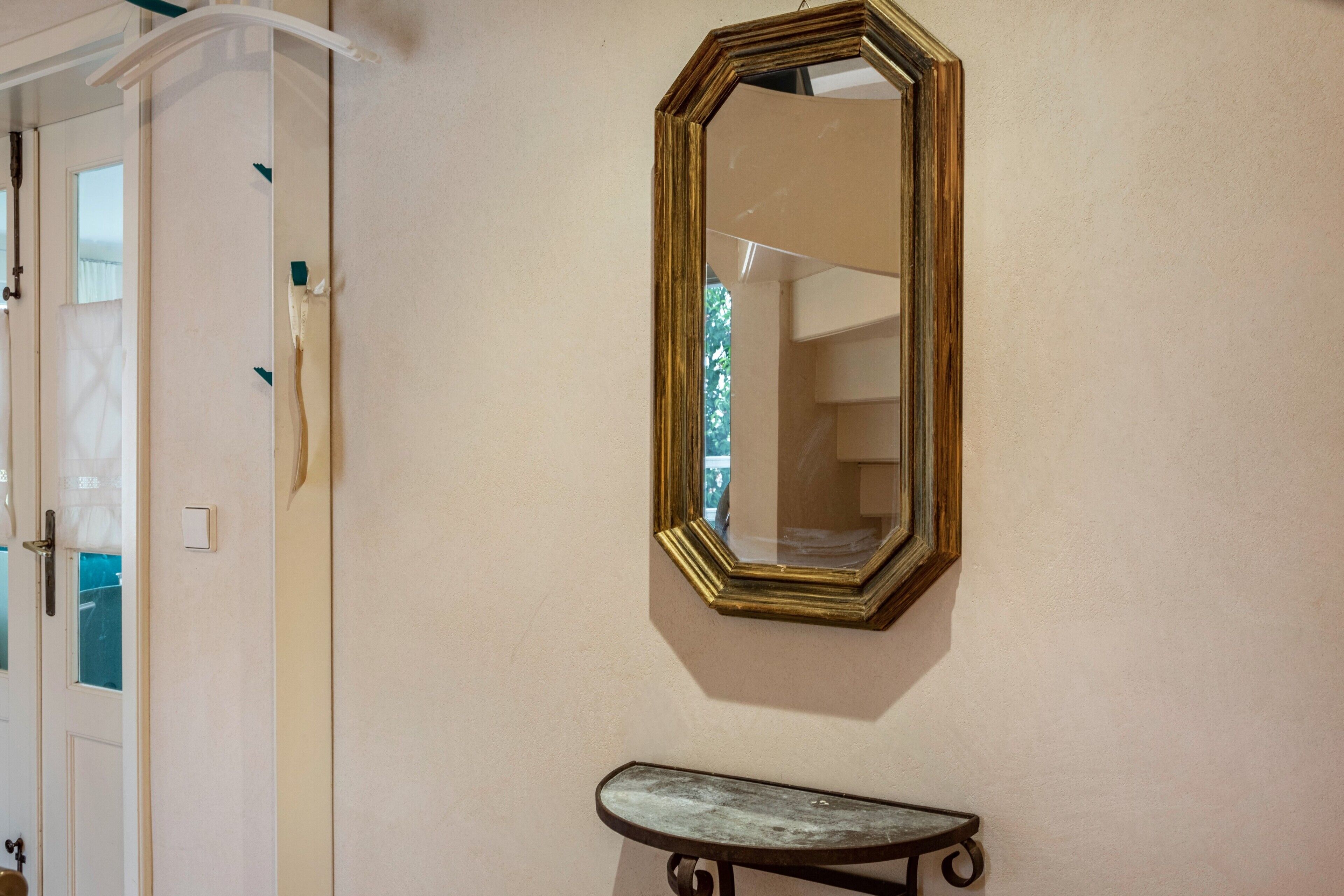 A room with a door, a wall-mounted mirror, and a small bench.