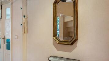 A room with a door, a wall-mounted mirror, and a small bench.