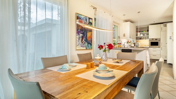 Un coin repas avec une table en bois, des chaises et un vase rempli de fleurs.