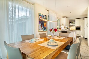 Un comedor con una mesa de madera, sillas y un jarrón con flores.