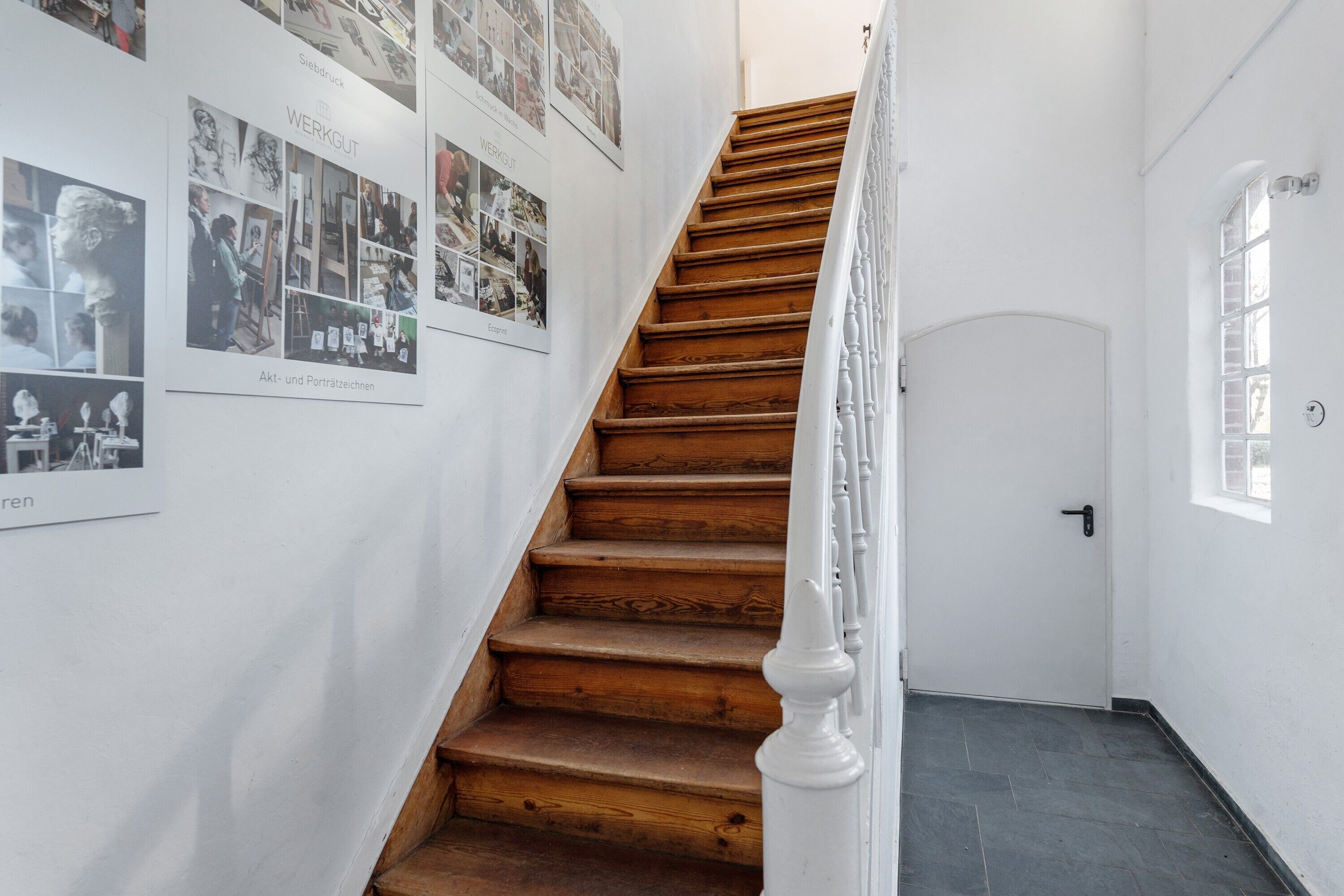 A staircase with wooden steps and white balusters, leading to a door with a small window.