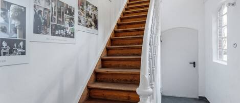 A staircase with wooden steps and white balusters, leading to a door with a small window.