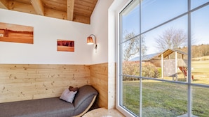 A wooden interior with a bench, a fluffy rug, and a window with a view of a wooden structure outside. - Geyerbad Holiday Home with Private Sauna – Dream Vacation High on the Swabian Alps (Meßstetten)