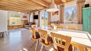 A wooden-paneled room with a dining table, chairs, and a television. - Geyerbad Holiday Home with Private Sauna – Dream Vacation High on the Swabian Alps (Meßstetten)