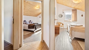 A bedroom with a wooden ceiling, a bed, a chair, and a window with curtains. - Geyerbad Holiday Home with Private Sauna – Dream Vacation High on the Swabian Alps (Meßstetten)