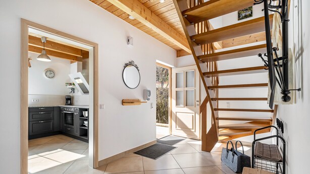 A modern kitchen with dark cabinets, a wooden staircase, and a view to the outside. - Geyerbad Holiday Home with Private Sauna – Dream Vacation High on the Swabian Alps (Meßstetten)