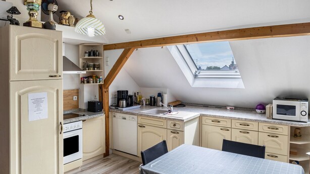 Una cocina con comedor, vigas de madera, tragaluz y vista a un edificio.