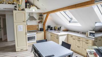 Una cocina compacta con comedor, horno empotrado y un ventanal grande.