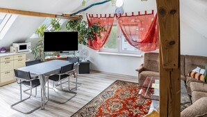 Una habitación moderna estilo loft con comedor, sofá y televisor.