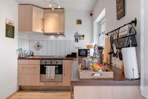 A modern kitchen with wooden cabinets, a microwave, and a fruit basket on the counter.