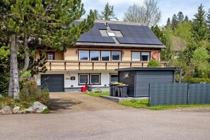 A two-story house with a garage, solar panels, and a fenced yard.