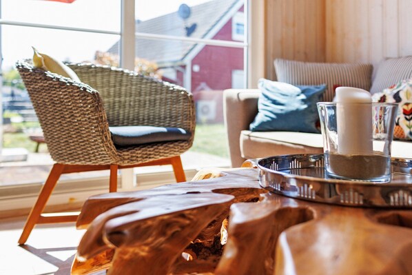 A wicker chair, a wooden coffee table, and a glass with a candle. - Holiday Home 'Annes Bootshaus' with Lake View, Private Terrace and Wi-Fi (Wandlitz-Zerpenschleuse)