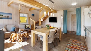 A wooden interior with a dining table, chairs, a staircase, and a kitchen area.
